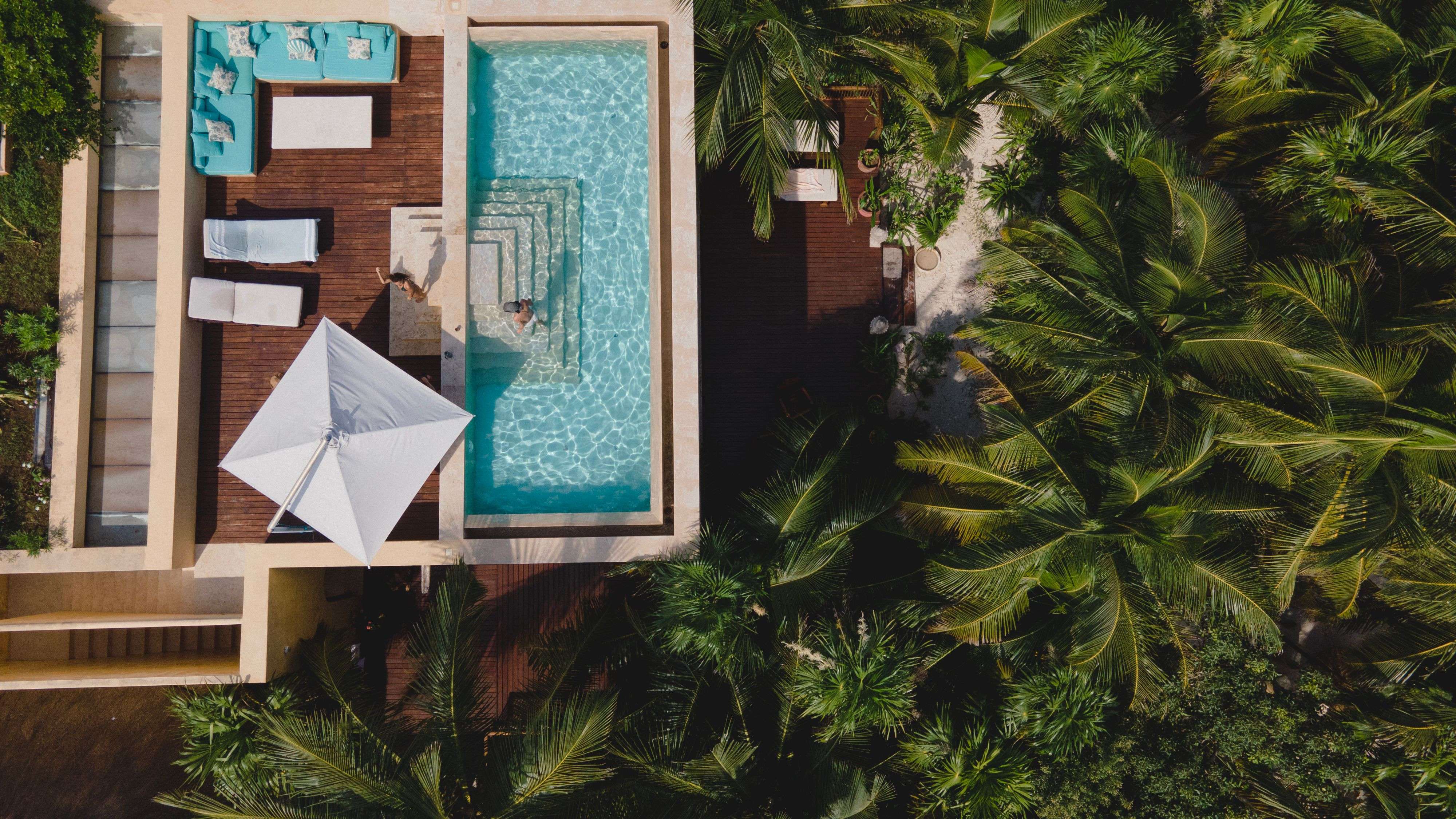 Aerial view of a modern villa with a private pool and outdoor lounge area surrounded by lush greenery